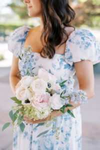 Bridesmaid holding a soft floral bouquet with white and blush blooms, accented by subtle French bleu details in her gown.