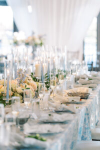 Elegant French bleu wedding tablescape with soft blue linens, white florals, glass candleholders, and refined place settings.