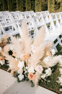 Ceremony aisle florals featuring soft neutral blooms and pampas grass accents