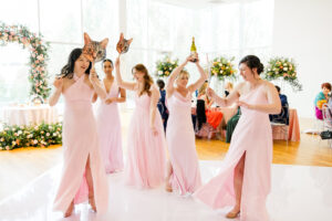 Wedding party making a lively grand entrance into the reception as guests cheer and celebrate.