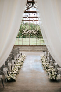 Indoor wedding ceremony aisle with white florals and draped entrance at a Columbus Ohio venue