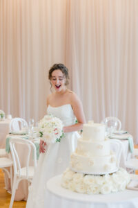 Bride laughing joyfully during her wedding reception near the cake display