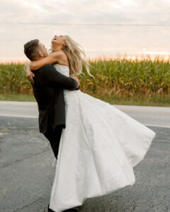 Groom lifting the bride in a joyful embrace during their wedding day celebration
