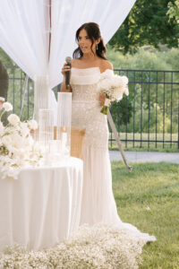 Bride holding her bouquet and speaking during a wedding reception dedication honoring her mother